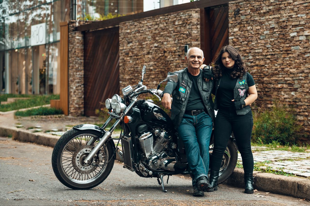 Father and daughter pose with motorcycle in urban setting. Casual style and street vibe.